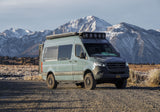 Custom 4x4 Mercedes Sprinter camper van RV rental, parked on a dirt road with majestic snowy mountains.