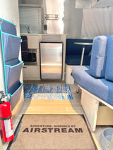 Compact Airstream RV rental interior with kitchenette, blue lounge, & smart storage. Ready for adventure!