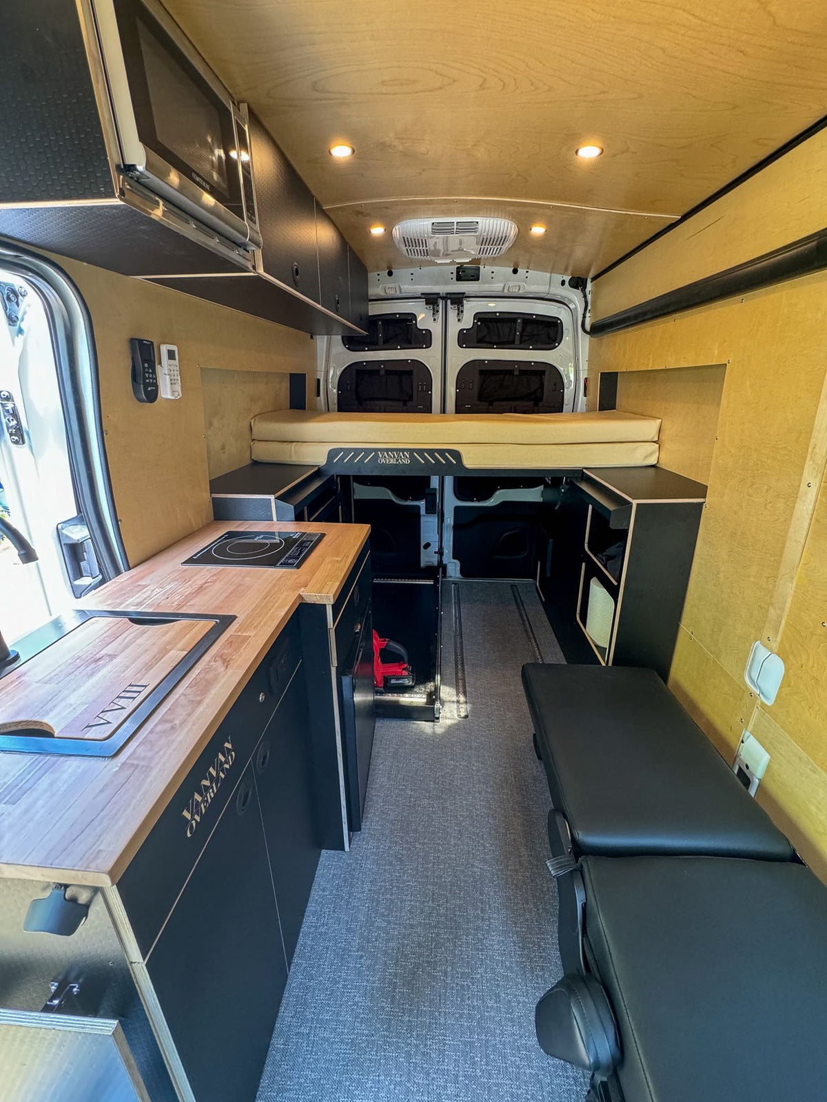  and wooden counter. Ready for travel.|RV rental interior: Versatile black padded seating converts to a bed — photo 15