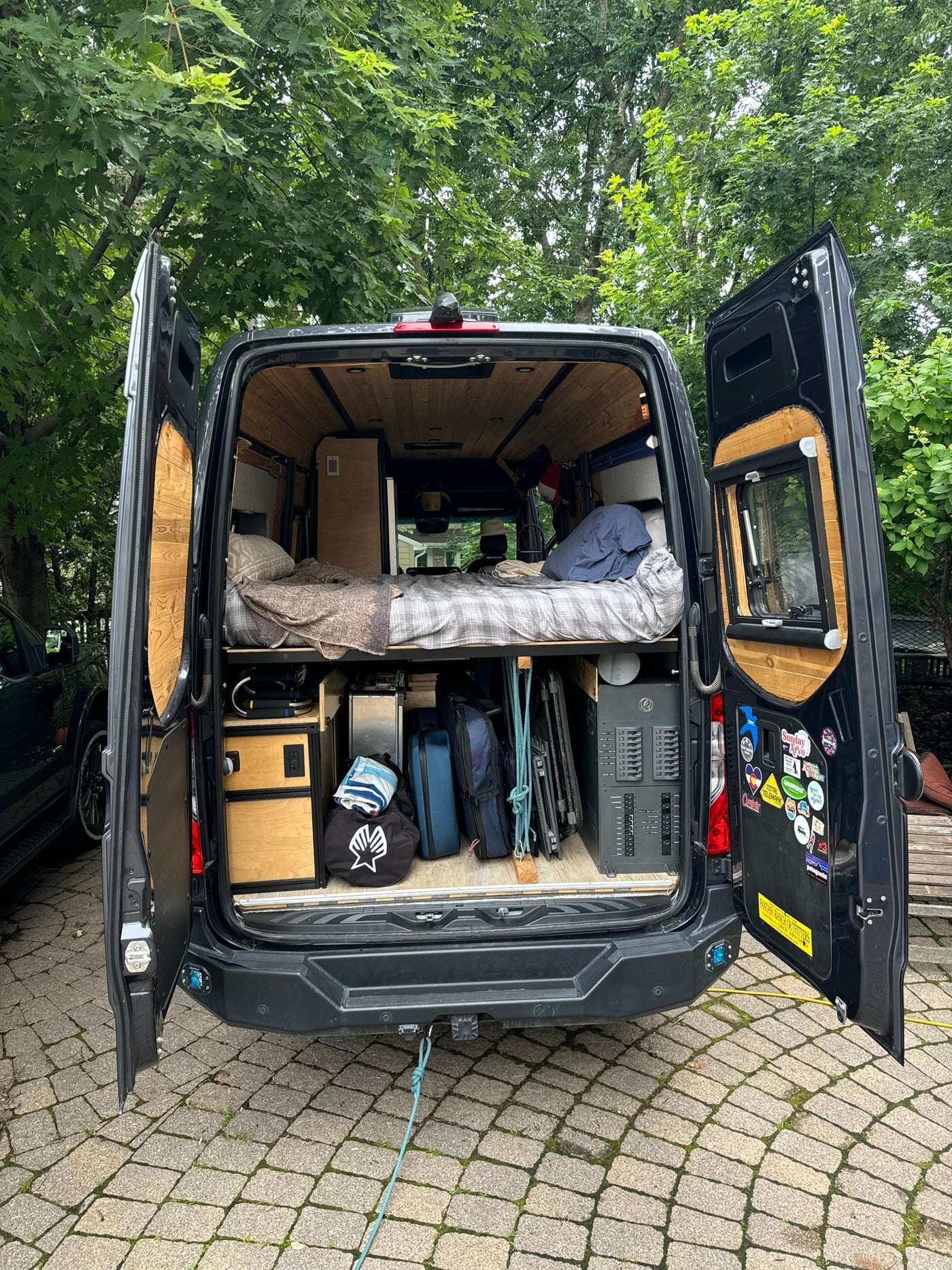  parked beside a dark gray camper van.|This RV rental camper van features an outdoor shower — photo 16