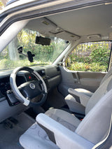 Interior of a Volkswagen van: gray seats, dashboard, and steering wheel, set for an RV rental journey.