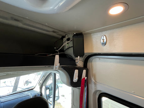 RV rental interior: Overhead storage, phone charging station, and organization hooks for mobile living in a camper van.