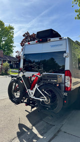 RV rental Winnebago van with two e-bikes on a hitch rack. Perfect for outdoor adventures, parked on a sunny residential street.