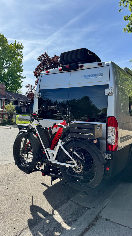 RV rental Winnebago van with two e-bikes on a hitch rack. Perfect for outdoor adventures, parked on a sunny residential street.