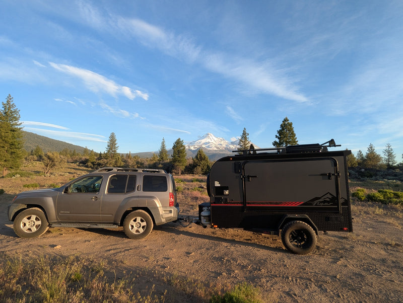 A gray SUV tows an off-road RV rental trailer, parked with stunning snow-capped mountain views for your adventure. — photo 3