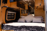 This cozy rv rental interior features a custom wood build, comfy bed, and clever storage for your next adventure.