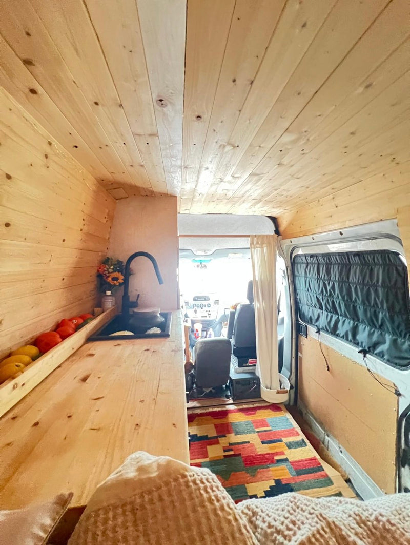Cozy RV rental interior: wood-paneled camper van with kitchen counter — photo 1
