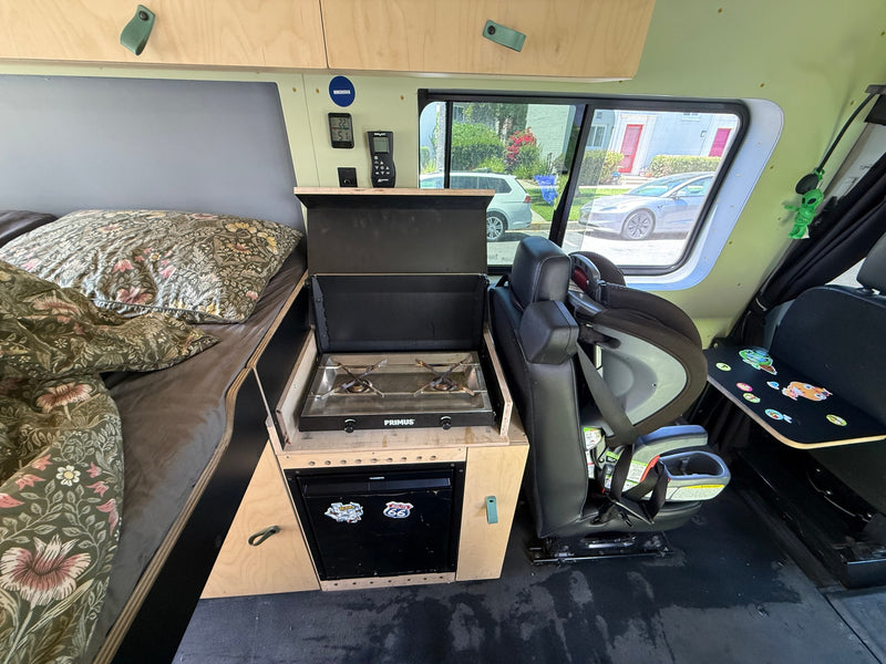 Cozy RV rental interior with a compact kitchen, comfortable bed, and child seat, ready for family adventures. — photo 12