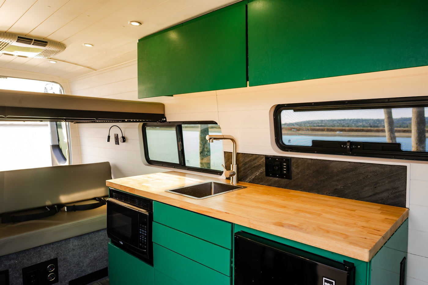  and interior light switches.|Modern RV rental interior features a vibrant green kitchen with microwave — photo 4