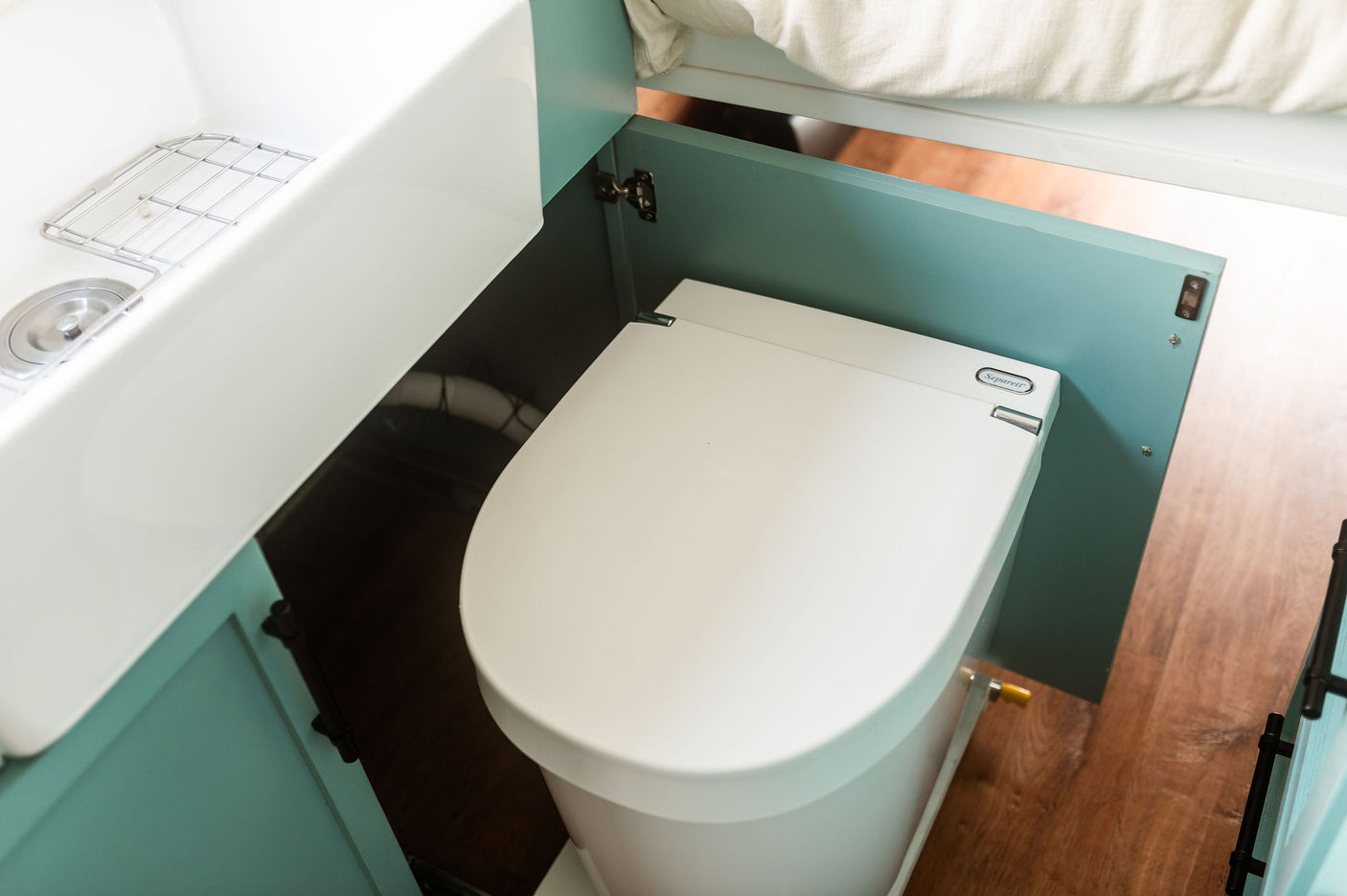 Compact RV rental bathroom: Separett composting toilet & white sink.