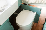 Compact RV rental bathroom: Separett composting toilet & white sink.