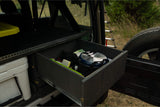 Organized RV rental: A custom pull-out drawer with camping gear, next to a cooler in vehicle storage.