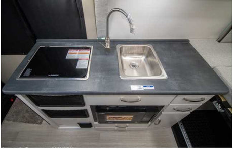 RV rental kitchenette featuring a sink, Dometic induction cooktop, and built-in microwave for easy meal prep on the road.