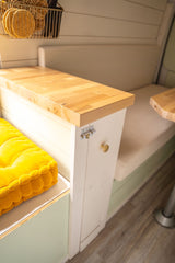 Discover this RV rental's clever interior: wooden counter, bright yellow cushion, and light built-in seating/storage.