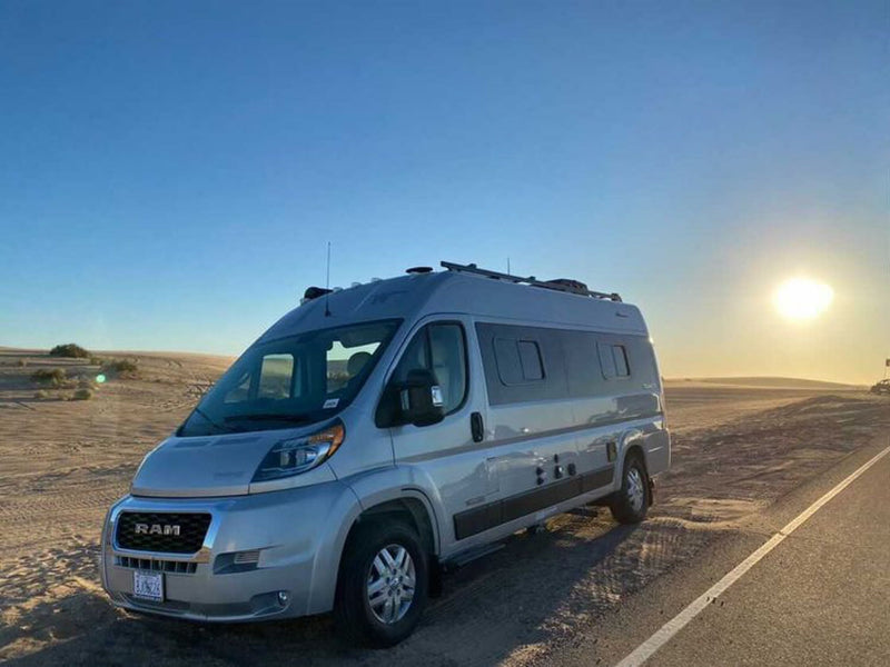 Silver RV rental camper van at desert sunset. Parked by the road — photo 1