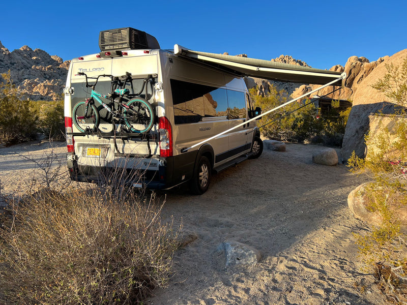  surrounded by rock formations and a nearby outhouse. Ideal for adventure.|A white Ram ProMaster RV rental — photo 5
