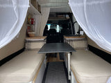 Cozy RV rental interior with convertible seating/beds, dining table, and storage. Ideal for comfortable mobile living.