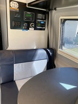 RV rental dinette with a detailed control panel: Zamp Solar charge (13.3V), Xantrex inverter, water/battery levels, and Euroloft controls.