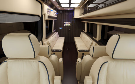 Luxury RV rental interior showcasing cream leather captain's chairs & sofas, dark wood, TV, and ambient lighting.