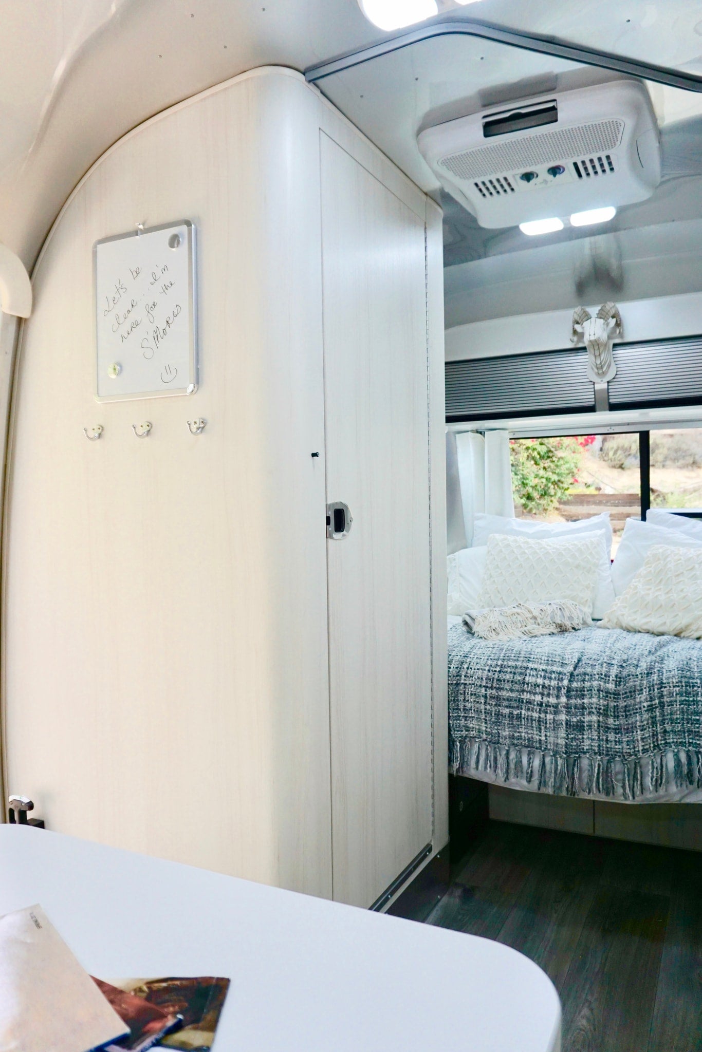 Cozy rv rental interior with light wood walls and ceiling, a bed with a cozy blanket, and a white memo board. — photo 16