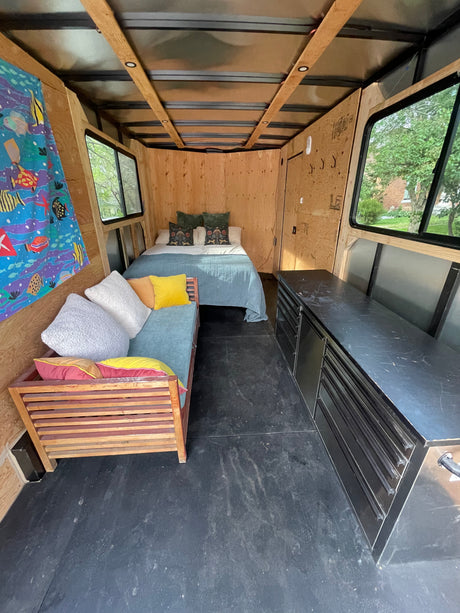 Cozy RV rental interior: a converted trailer featuring a bed, bench seating, and storage for your next adventure.