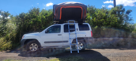 White SUV with a large rooftop tent & ladder, ready for your rv rental camping adventure. Ideal for overlanding!
