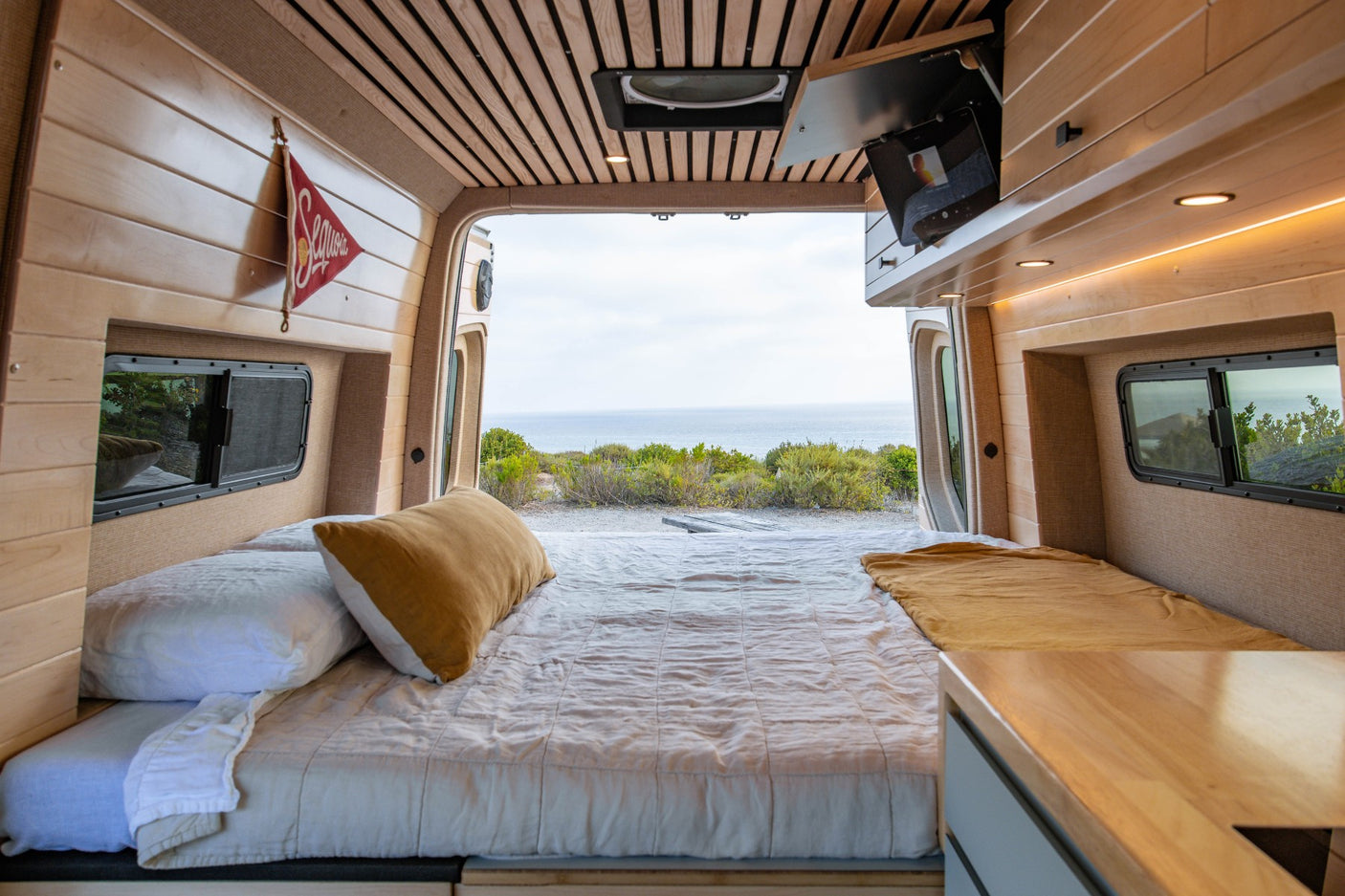 This cozy RV rental van offers a stunning ocean view from its comfortable bed, perfect for serene getaways.