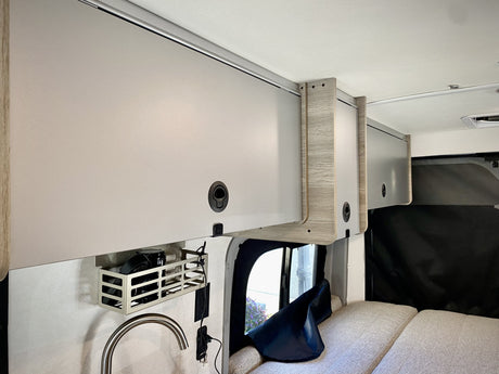 RV rental: Modern camper van interior featuring sleek overhead storage, a compact kitchenette, and plush sleeping area.