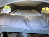Comfortable pop-top bed in an RV rental, offering a cozy retreat with nature views through the side windows.