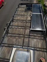 Top-down view of an RV rental van's roof rack with solar panels, fan, and skylight.