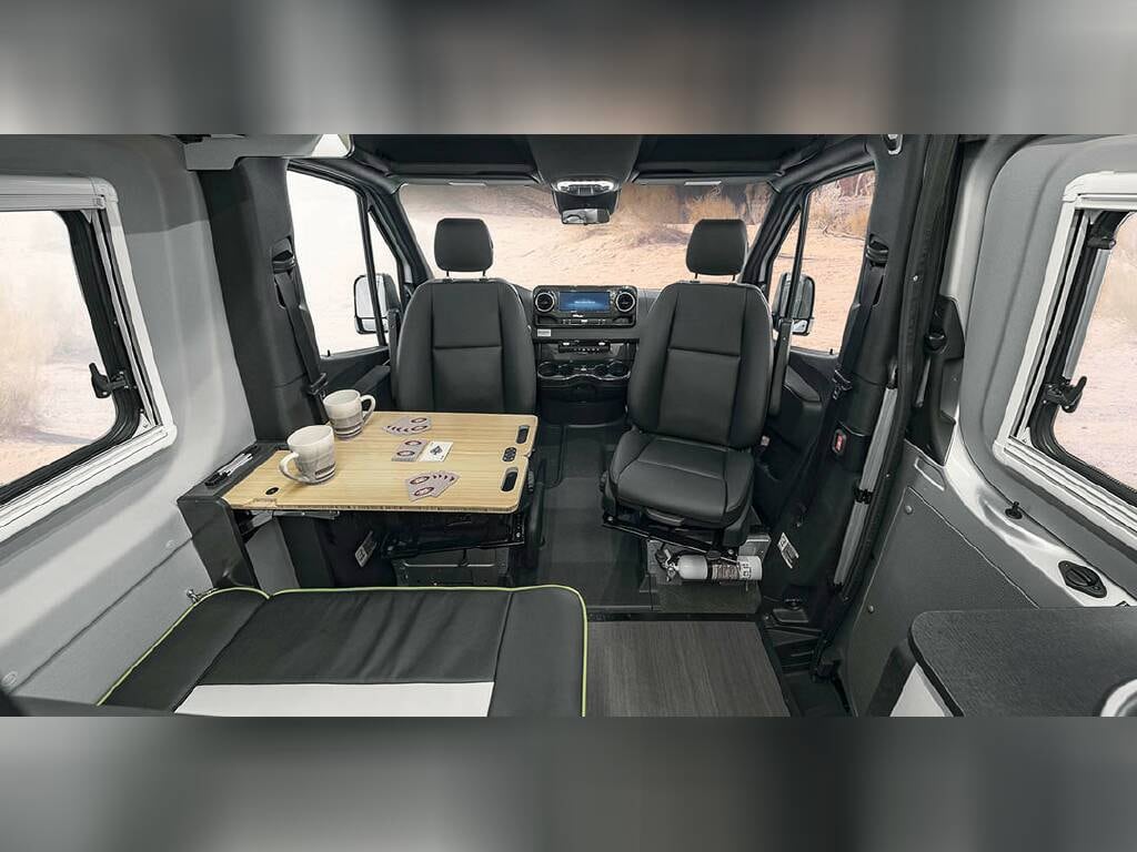  ideal for your next RV rental journey. Parked on a scenic dirt hill overlooking a city.|Retro-striped silver Sprinter camper van on a dirt hill — photo 3