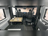 Spacious RV rental interior with swiveling front seats, a pull-out table for games, and a cozy bench bed. Perfect for travel.