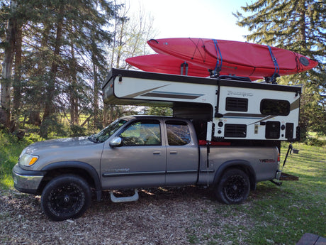 A Toyota Tundra with a Palomino truck camper and kayaks. Perfect for an adventure, like an RV rental!