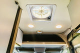 RV rental interior showing a ceiling fan, two bright lights, a smoke detector, and overhead storage.