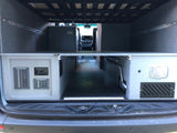 Rear interior of an RV rental camper van, showing under-bed storage, electrical controls, and a central aisle.