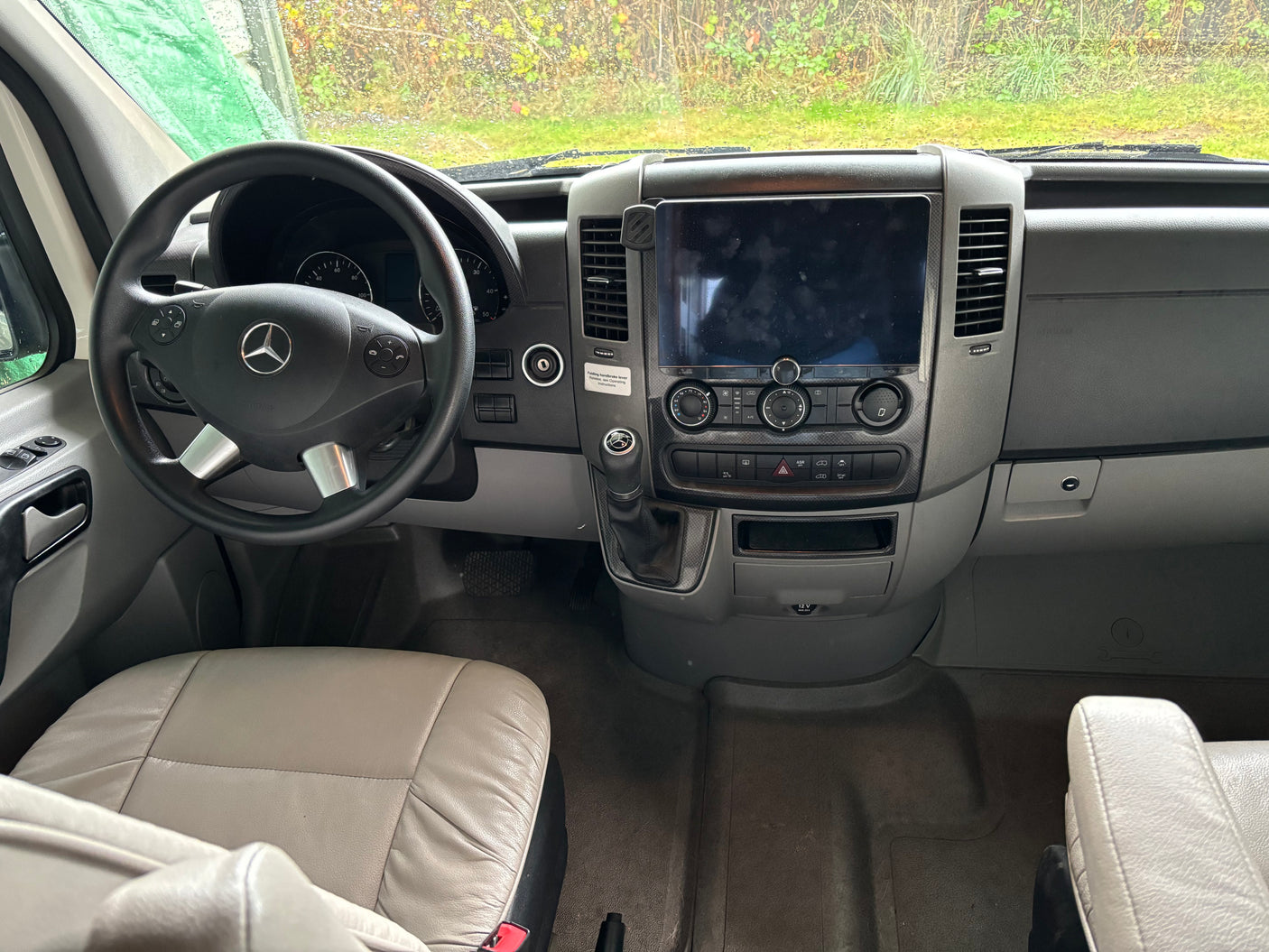 Inside an RV rental: the driver's view of the dashboard with a Mercedes steering wheel, large screen, and various controls.