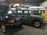 A lineup of Land Rover SUVs, including classic models, outfitted with rooftop tents. Perfect RV rental for overland adventures.