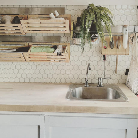 RV rental kitchen with organized wooden storage, a small sink, and a white hexagonal tile backsplash.