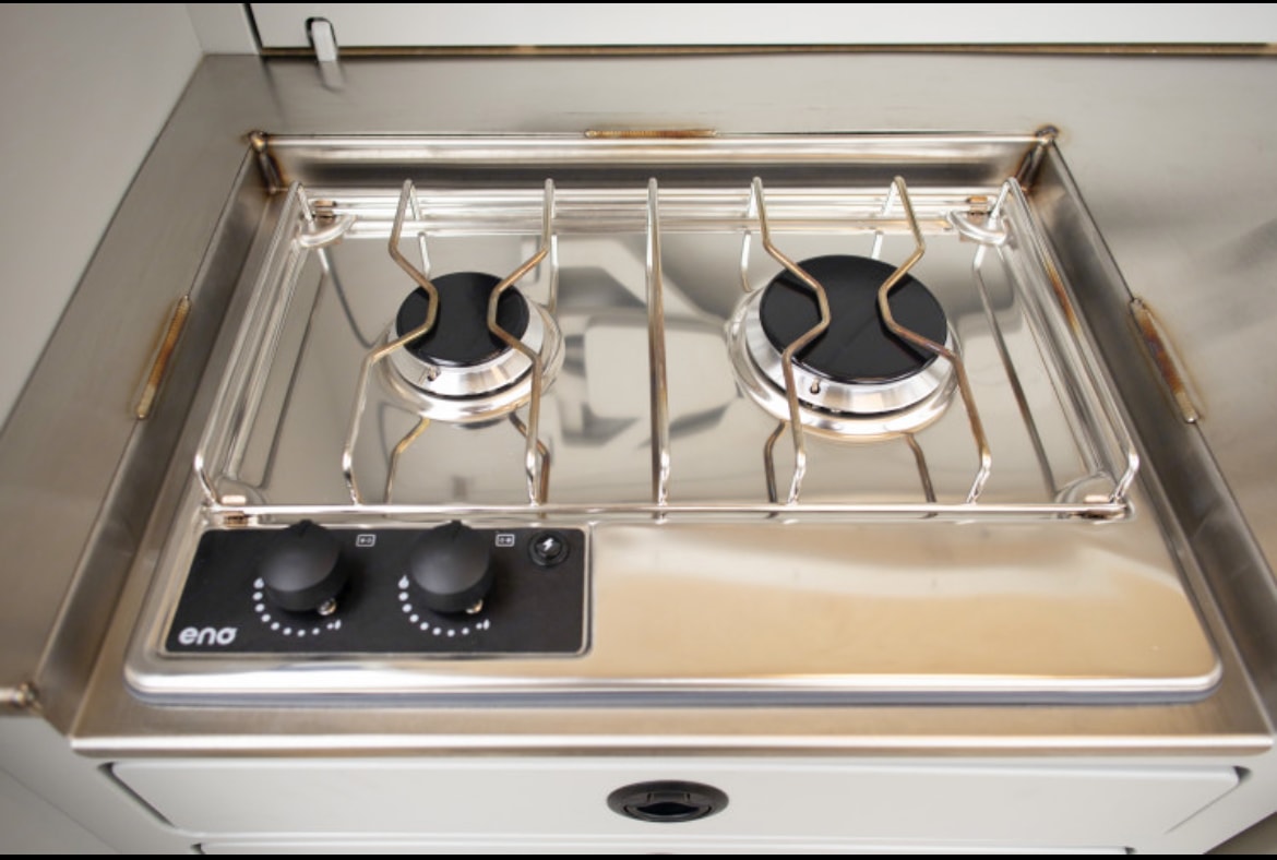 Inside an RV rental, a compact stainless steel two-burner gas stove features black control knobs for cooking ease. — photo 6