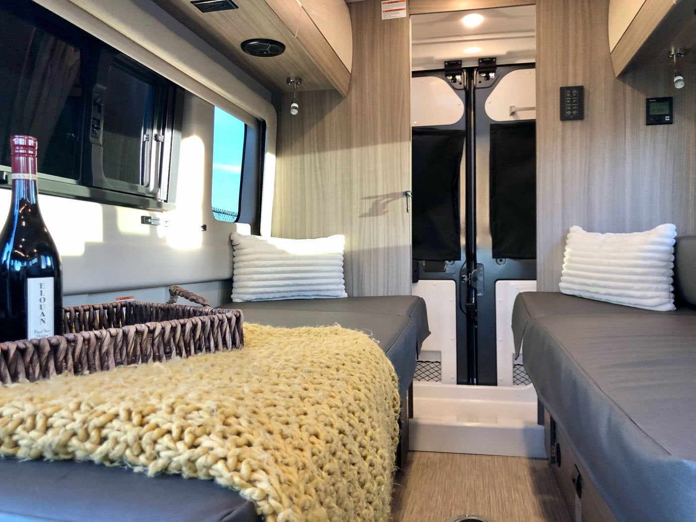 Cozy RV rental interior with comfortable seating, a warm blanket, and wine. Perfect for your next adventure. — photo 4