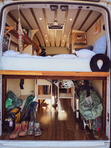 Comfy camper van RV rental interior: raised bed, lower storage for boots/chairs, perfect for adventure.