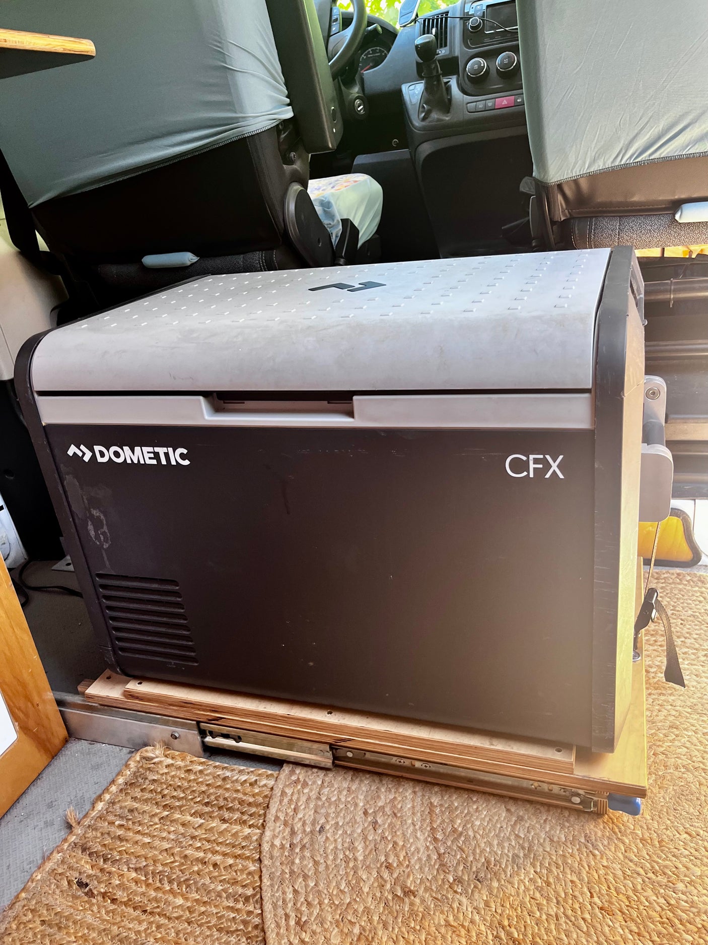 A Dometic CFX portable fridge, on a slide-out tray, ready for your rv rental trips. Seen in a camper van interior.
