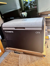 A Dometic CFX portable fridge, on a slide-out tray, ready for your rv rental trips. Seen in a camper van interior.
