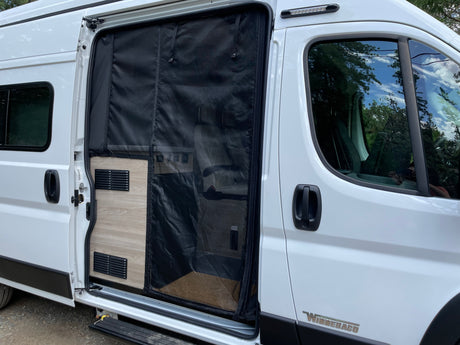 A white Winnebago RV rental with an open side door and bug screen, showing interior and exterior details.