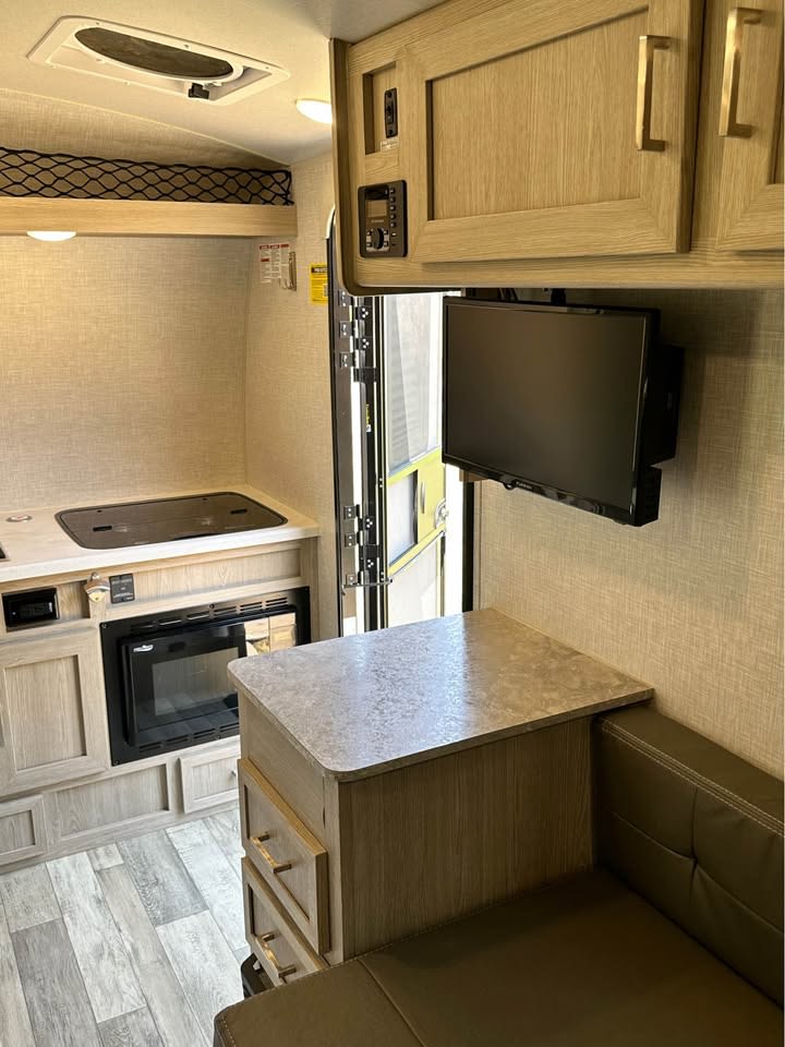 Modern RV rental interior features a compact kitchenette, dinette, and TV. Perfect for your next adventure. — photo 6