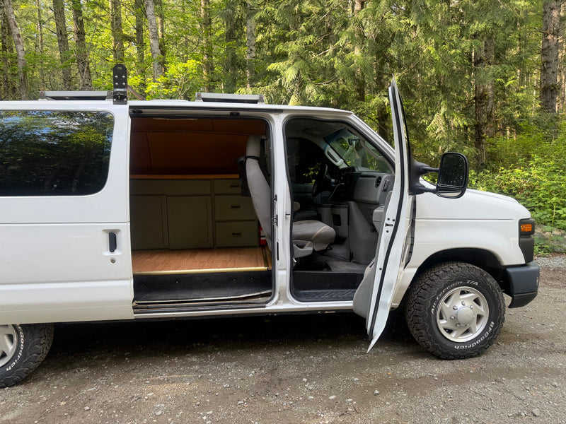 Open white camper van, showcasing custom wood interior & cabinets, parked in a lush forest. Perfect for an rv rental adventure. — photo 10