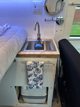 Inside an RV rental: compact kitchen sink, cozy bed, and a cleverly concealed portable toilet maximize small space living.