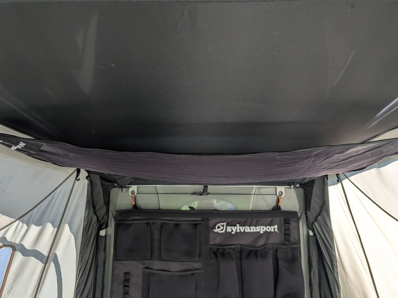  and bright green fabrics.|RV rental interior: SylvanSport pop-up camper's sleeping area with mattress and windows looking out onto a neighborhood.|Interior of a SylvanSport pop-up camper — photo 19