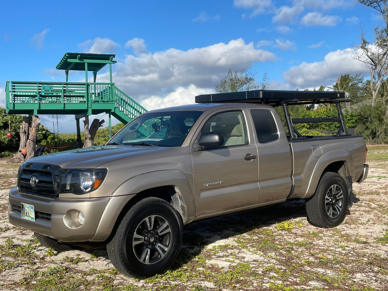 This tan Toyota Tacoma pickup, equipped for overlanding, offers a great RV rental alternative parked by a unique green treehouse. — photo 14