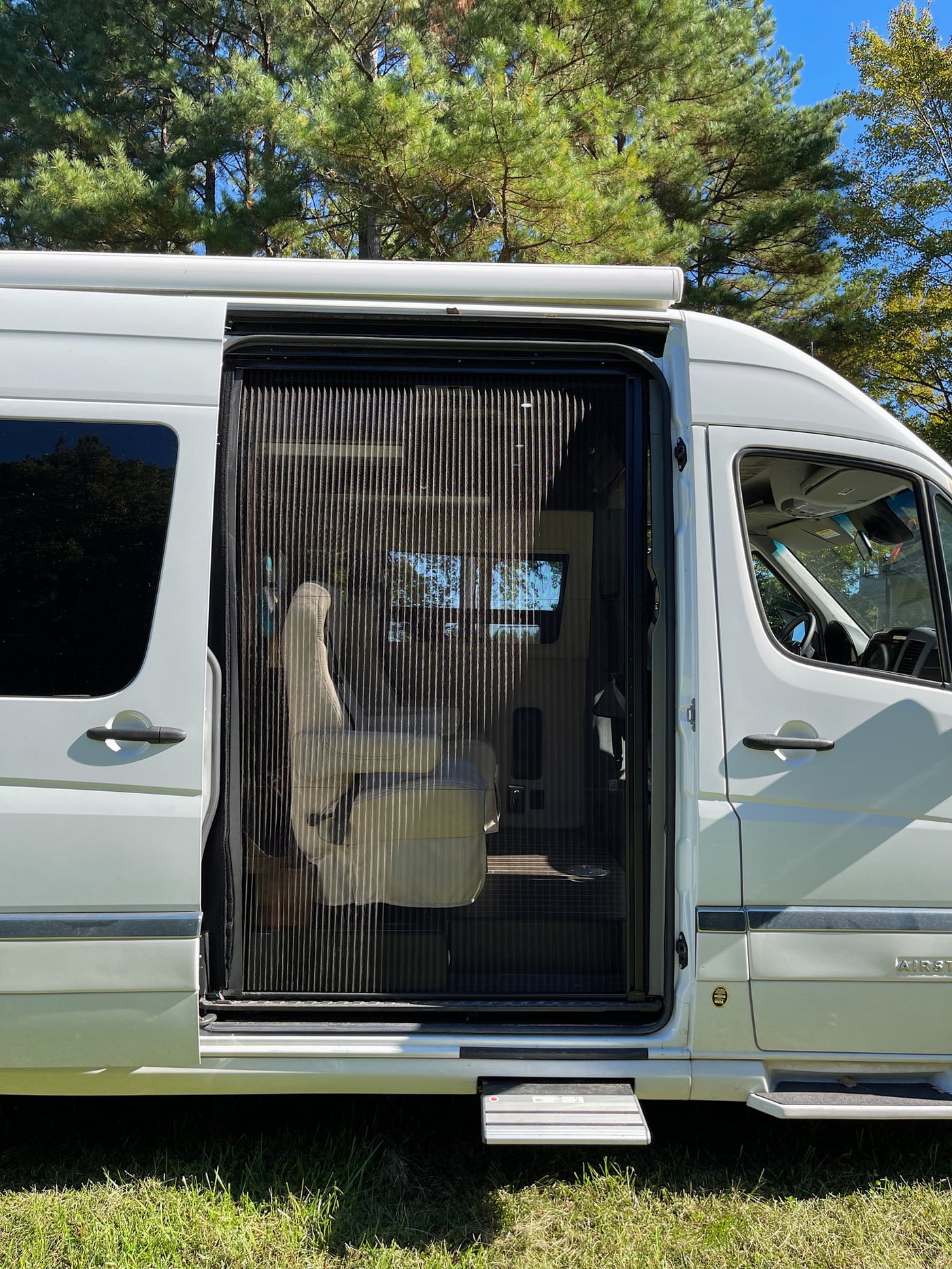 White RV rental with open side door, screen, and deployed step. Interior shows a swivel seat. Ideal for outdoor adventures. — photo 4